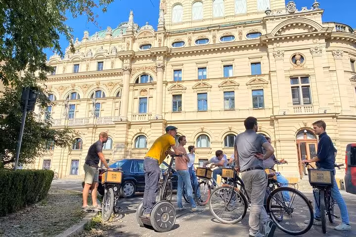 Group of cyclists gathers in front of a grand historic building in Krakow during a guided bike tour.