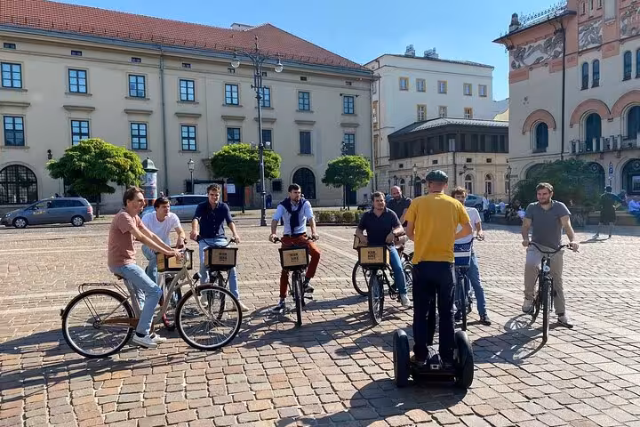 Group of cyclists with a guide on a Segway in Krakow's historic square during a guided bike tour.