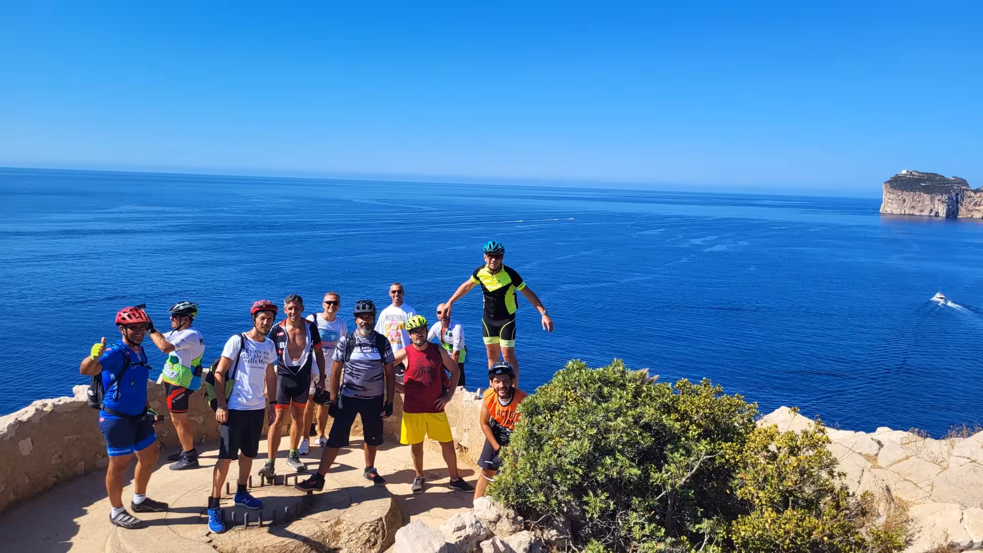 Group of cyclists enjoying scenic Alghero coastline during guided e-bike tour with stunning sea views.