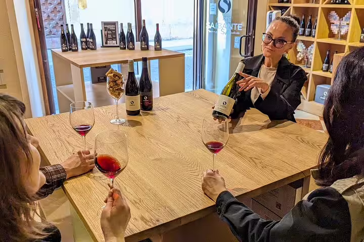 Wine tasting during a guided Verona food tour, guests sampling red wine at a local enoteca table
