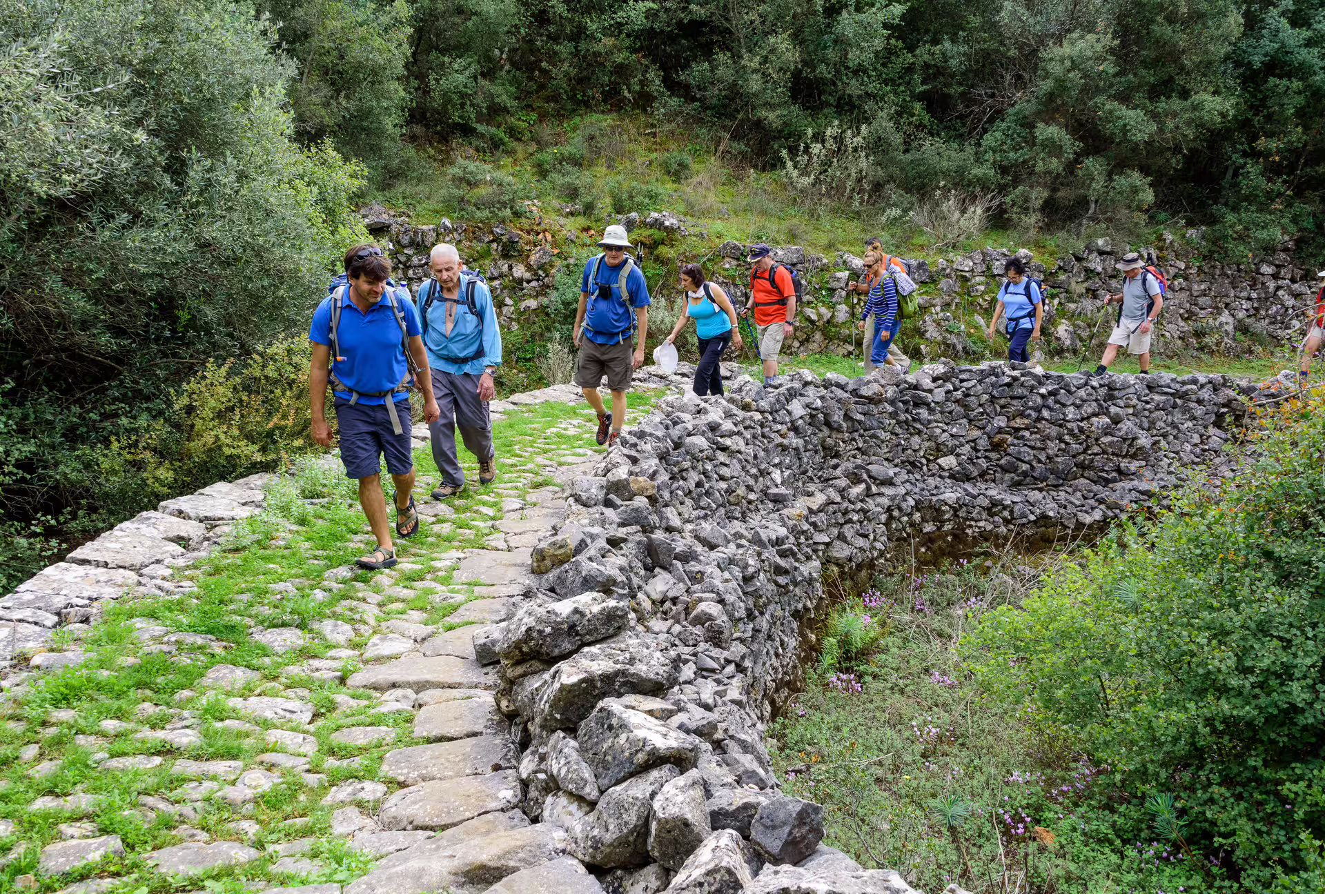 Guided hiking group crosses a stone bridge on the Kardamyli trail in the Mani, Peloponnese, Greece