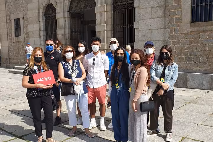 A group of tourists with masks gather for a guided tour in Avila during a day trip from Madrid.