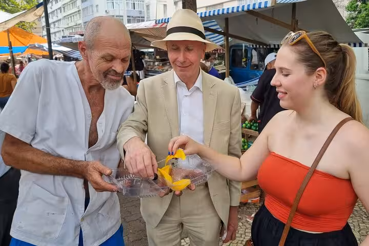 Tourists enjoying a guided tropical fruit tasting at a bustling market in Rio de Janeiro, sampling fresh produce.