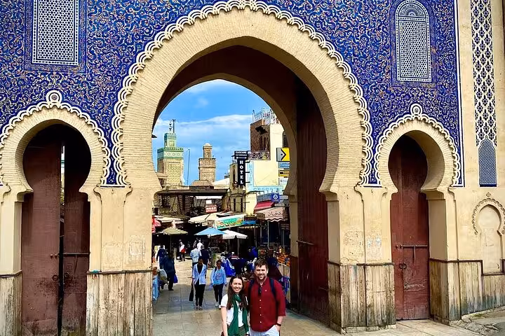 Tourists explore the iconic Bab Bou Jeloud gate in Fez's Old Medina during a guided walking tour.