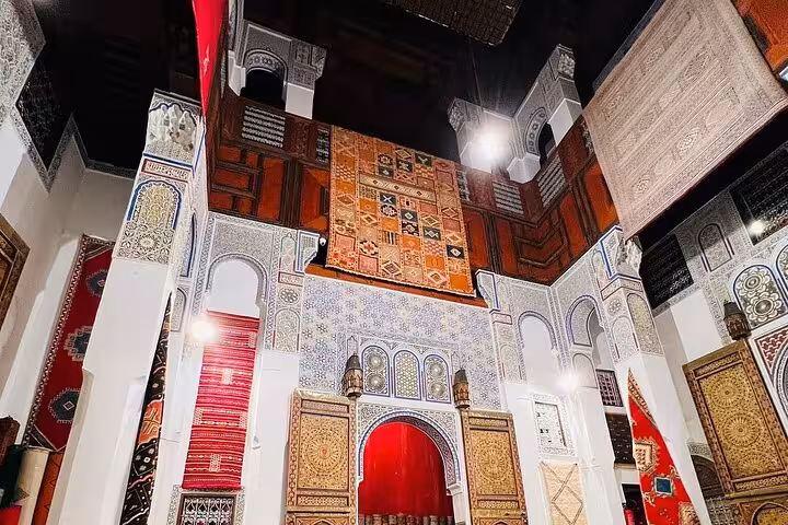 Colorful rugs and ornate architecture in a traditional Moroccan interior in the Old Medina of Fez.
