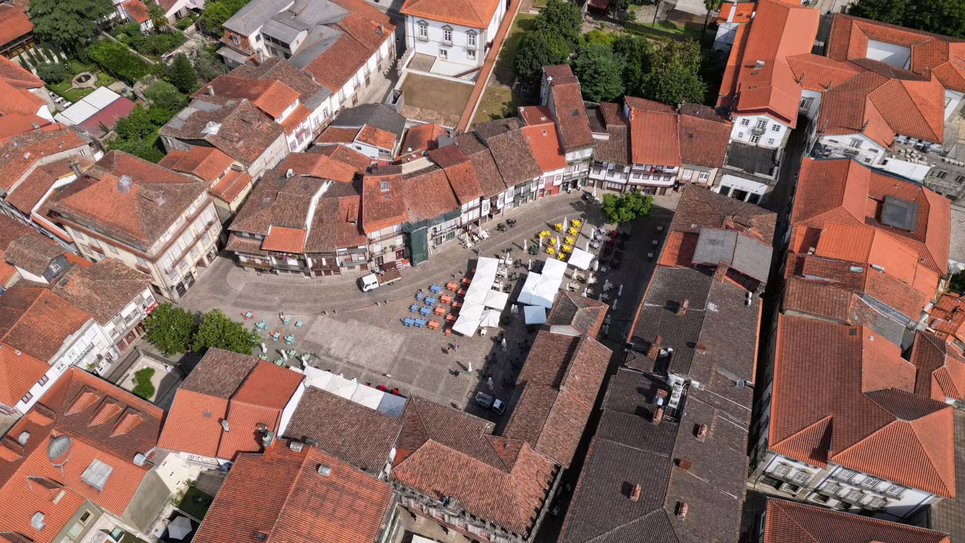 Aerial view of Guimarães' historic city center with charming red-roofed buildings and vibrant street cafes.