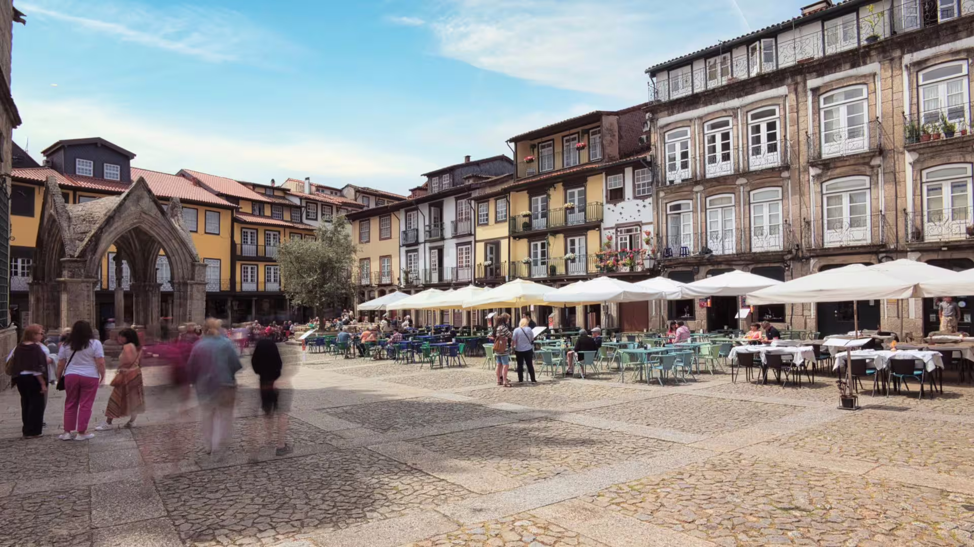 Scenic view of Guimarães square with historic buildings and outdoor cafes, ideal for a small group tour with lunch.
