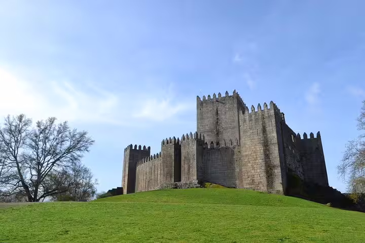 Majestic view of Guimarães Castle under a clear blue sky, a highlight of the Braga and Guimarães tour from Porto.