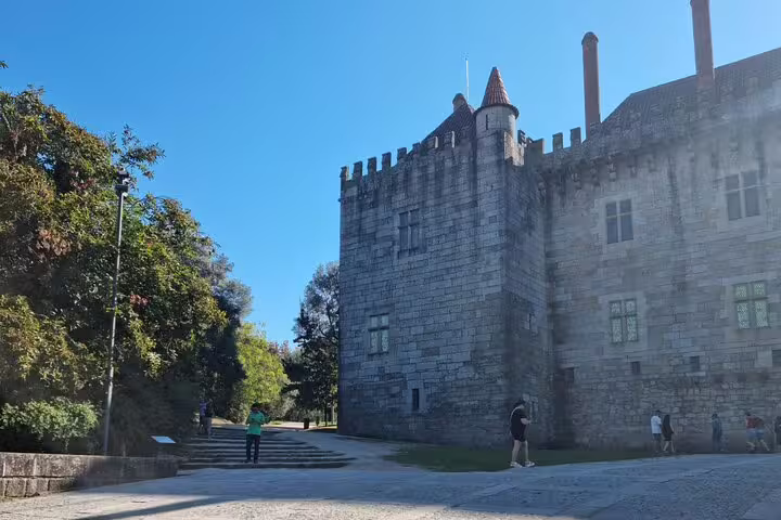 Visitors admire the medieval architecture of Guimarães Castle, a key attraction on the historic tour from Porto.