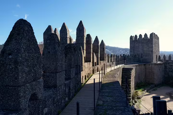 Guimarães Castle's ancient stone walls and towers under clear skies, showcasing Portugal's rich medieval heritage.