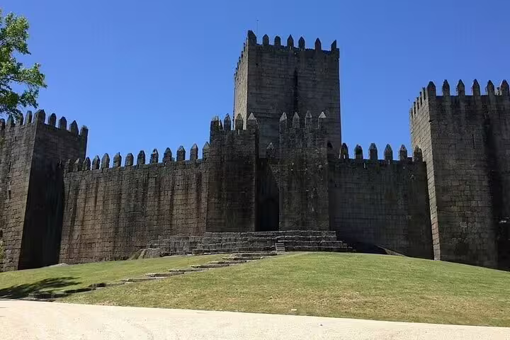 Guimarães Castle medieval stone walls under blue sky, must-see on Porto to Braga and Guimarães private tour