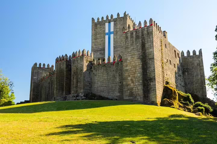 Explore the majestic Guimarães Castle under a clear blue sky, a highlight of the Minho Tour in Portugal.
