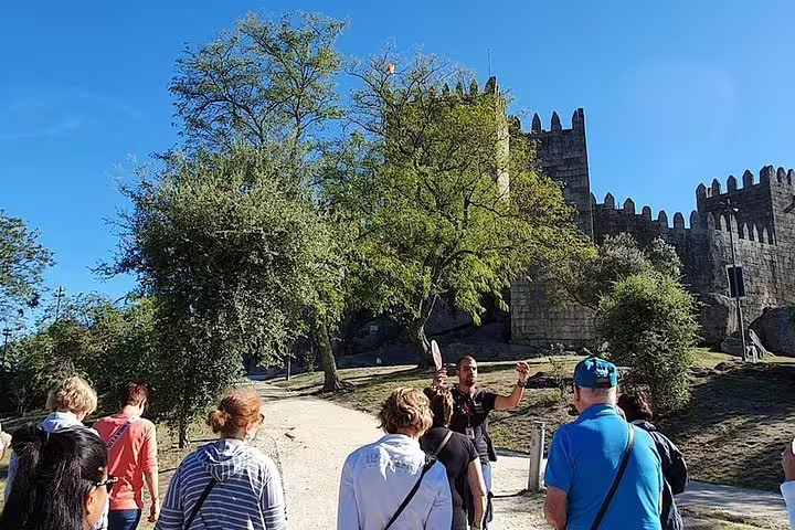 Visitors explore the historic Guimarães Castle grounds with a guide during the Minho Tour Private full-day tour.
