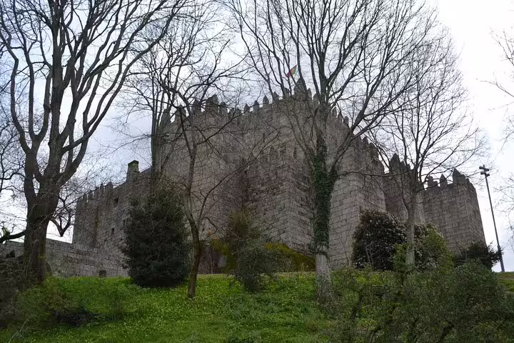 Majestic Guimarães Castle surrounded by trees, a highlight on the half-day private tour from Porto.