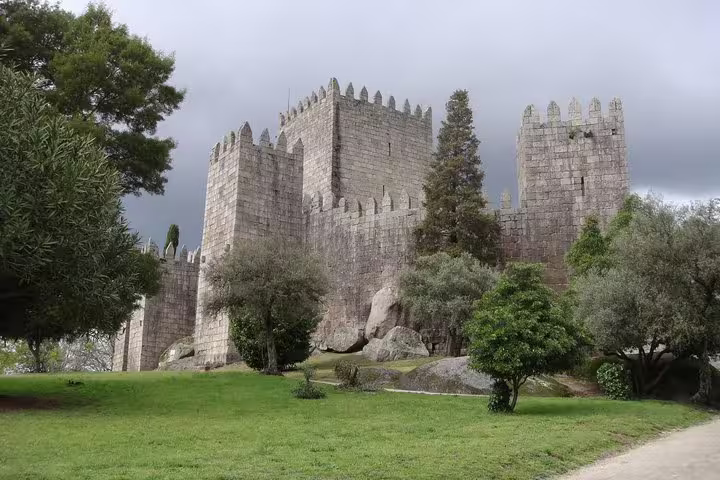Explore the historic Guimarães Castle surrounded by lush greenery on a full-day small group tour with lunch included.