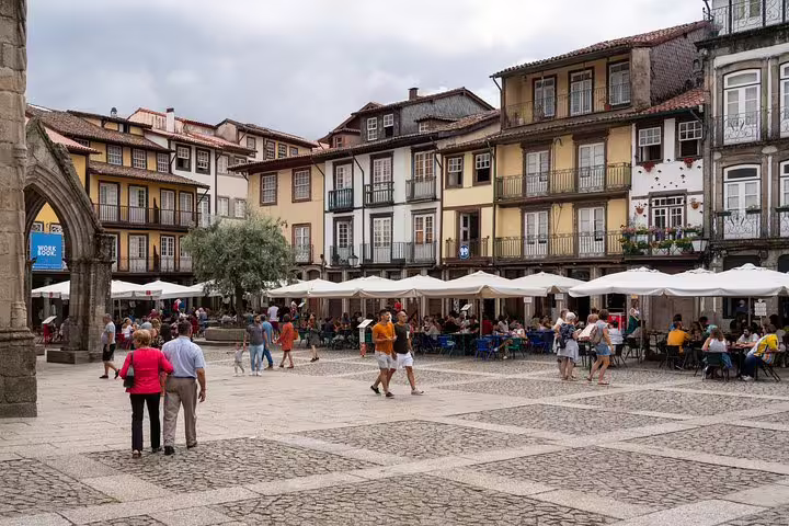 Visitors enjoy a lively square in Guimarães, surrounded by historic buildings and outdoor cafes on a Minho tour.