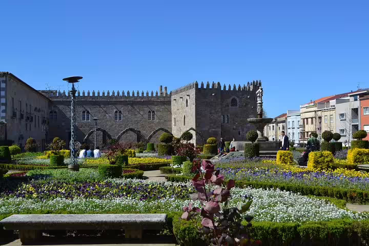 Vibrant flower gardens beside a medieval castle in Guimarães, highlighting cultural sights on a Porto day trip.