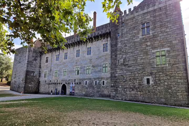Visit the majestic medieval castle in Guimarães on a private historic tour from Porto, surrounded by lush greenery.