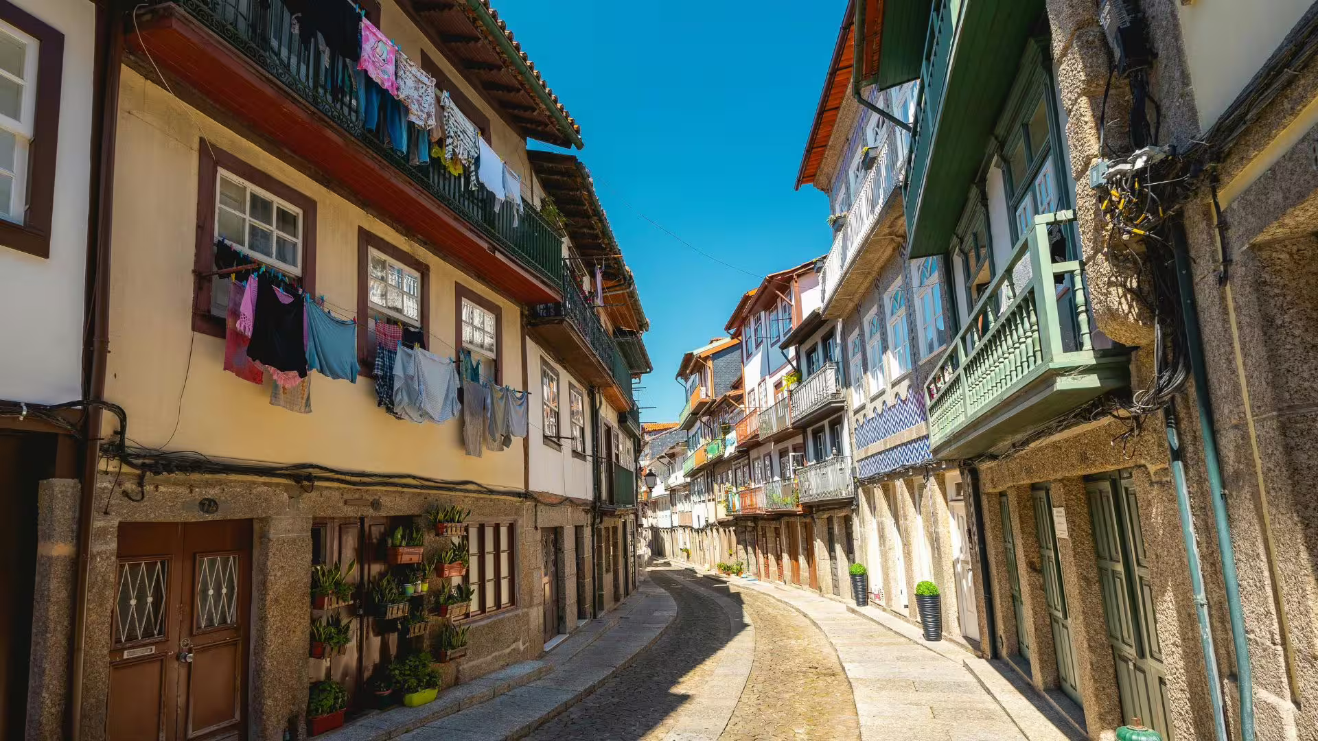 Charming narrow street in Guimarães with traditional Portuguese architecture on a sunny day.