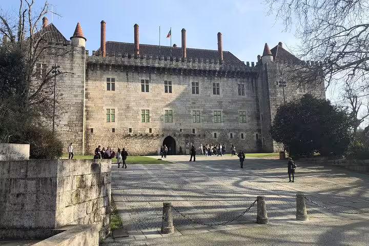 Visitors gather outside the grand façade of Guimarães Palace on a guided small group tour with lunch included.