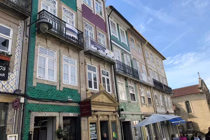 Colorful traditional buildings with charming balconies line a street in Guimarães under a clear blue sky.