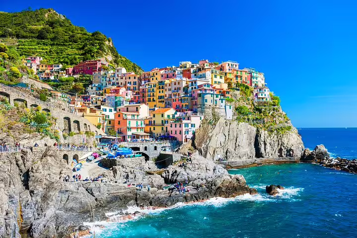 Colorful cliffside village overlooking turquoise Ligurian Sea on a sunny day, featured on a private Gulf of Poets boat tour