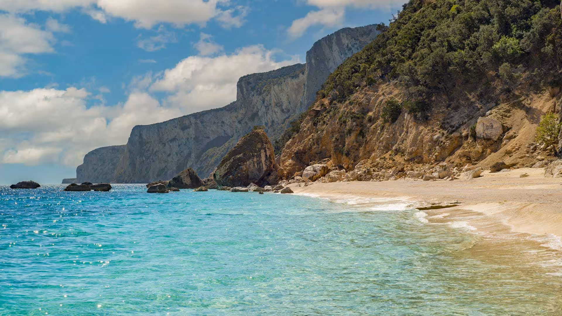 Pristine sandy beach with crystal-clear turquoise waters and dramatic cliffs in the Gulf of Orosei.