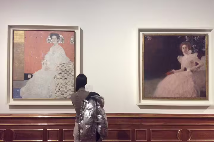 Visitor admiring Gustav Klimt paintings at the Belvedere in Vienna, highlighting the art tour experience.