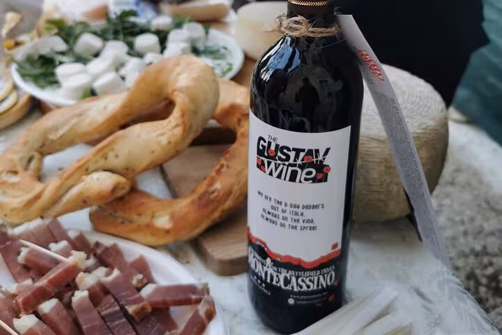 Close-up of Gustav Wine bottle surrounded by artisanal bread and cheese, capturing the essence of Monte Cassino flavors.