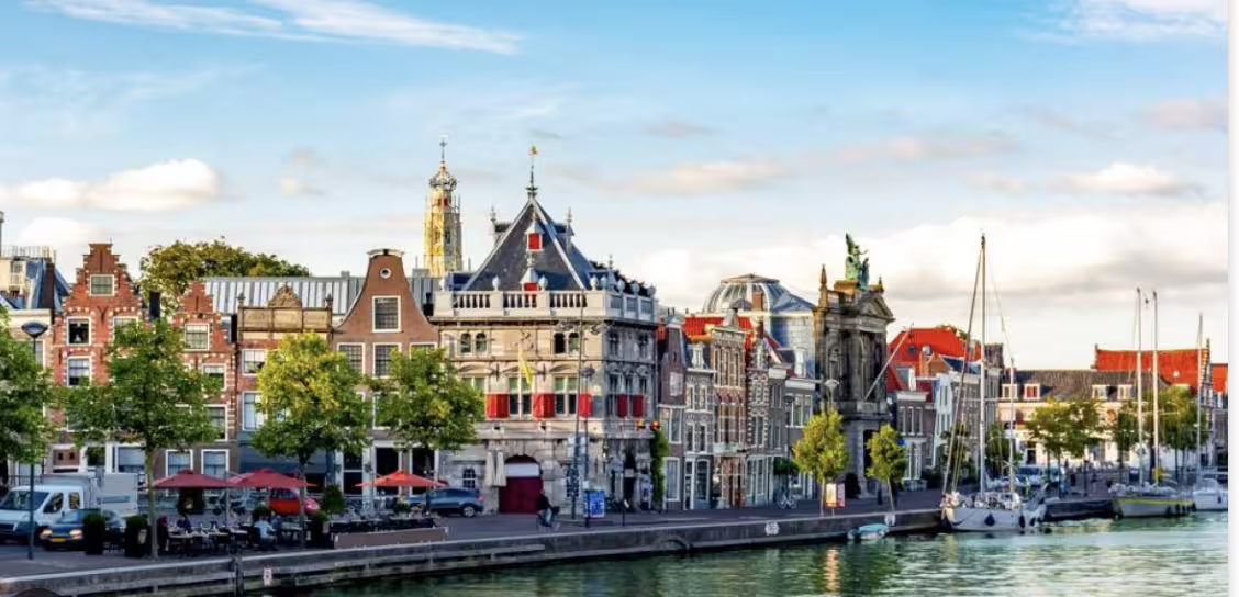 Scenic view of Haarlem's historic architecture along the canal, showcasing charming Dutch buildings and boats under a sunny sky.
