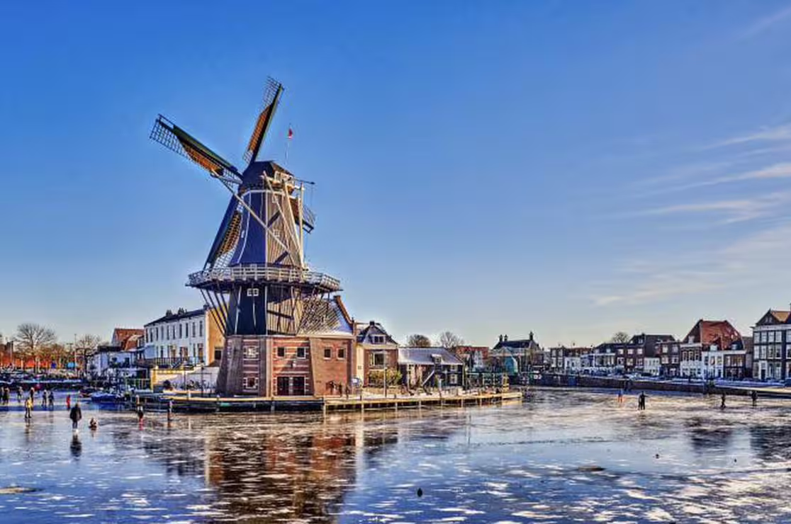 Windmill overlooking a frozen canal in Haarlem, Netherlands, a scenic highlight on the walking tour from Amsterdam by train.