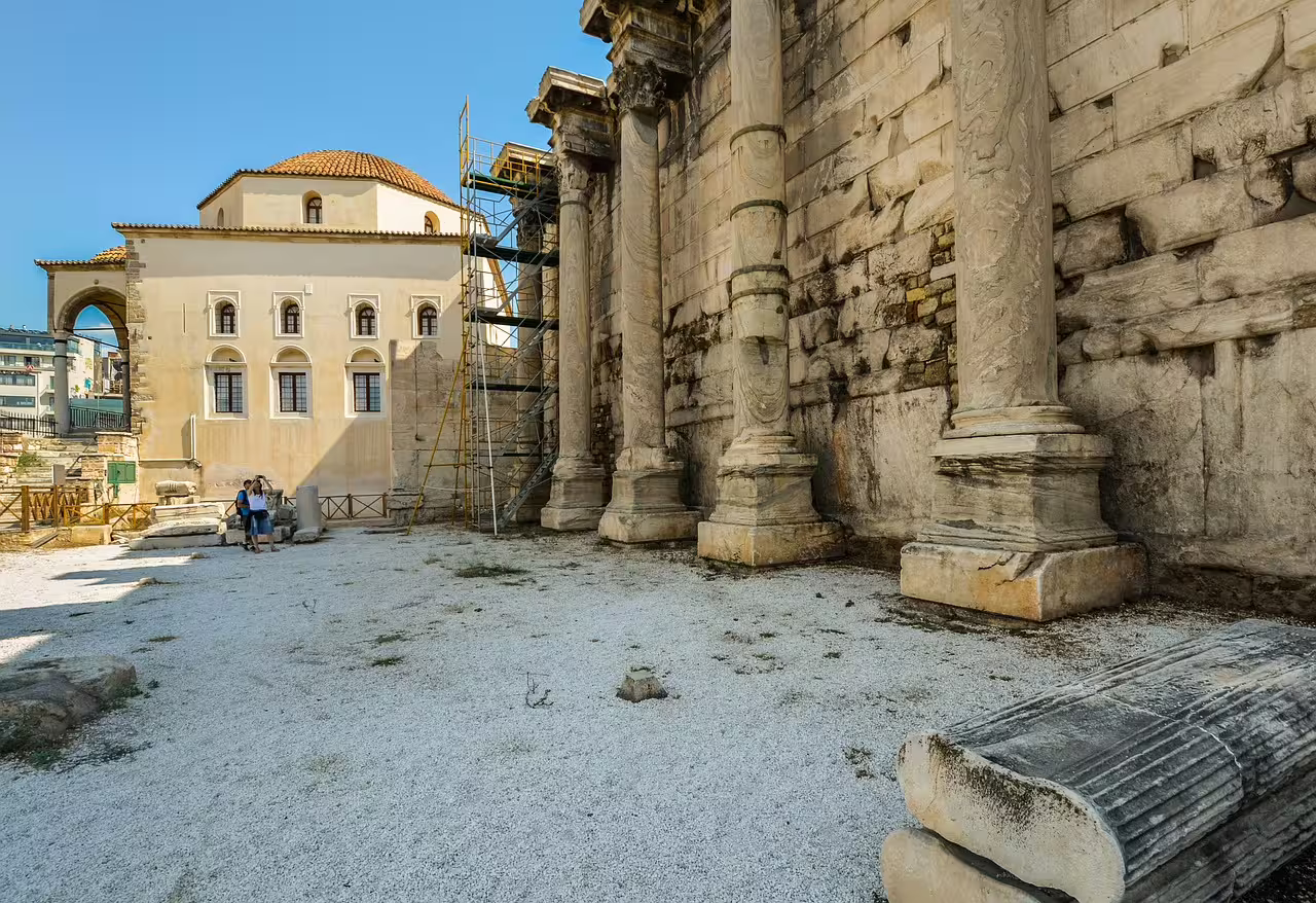 View of Hadrian's Library in Athens, featuring ancient columns and architectural restoration under a clear blue sky.