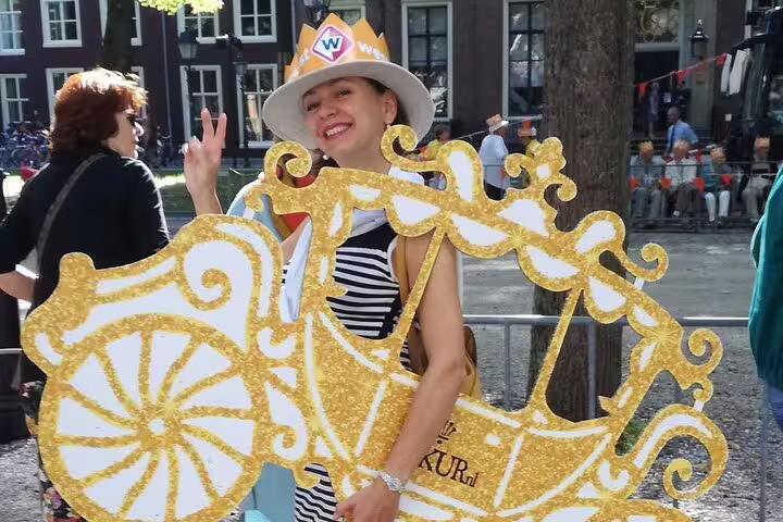 Visitor posing in golden carriage cutout at The Hague festival, a fun moment on Your Own Hague tour