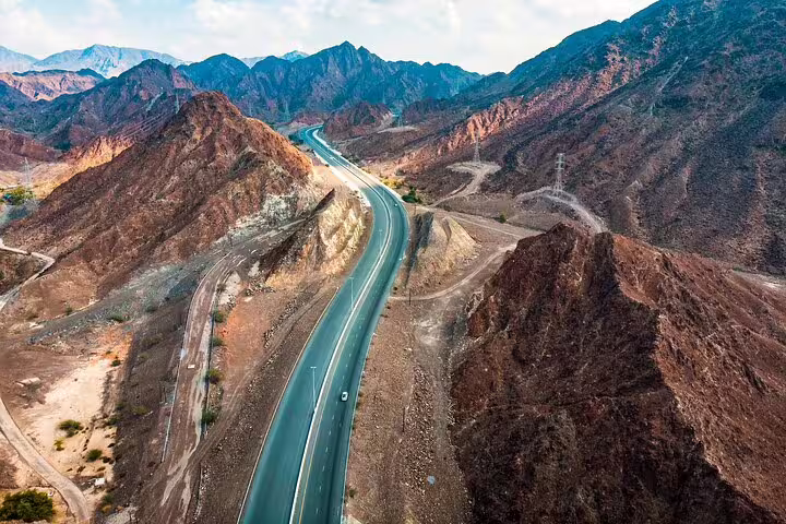 Scenic view of a winding highway through the rugged Hajar Mountains on the Six Emirates tour from Dubai.