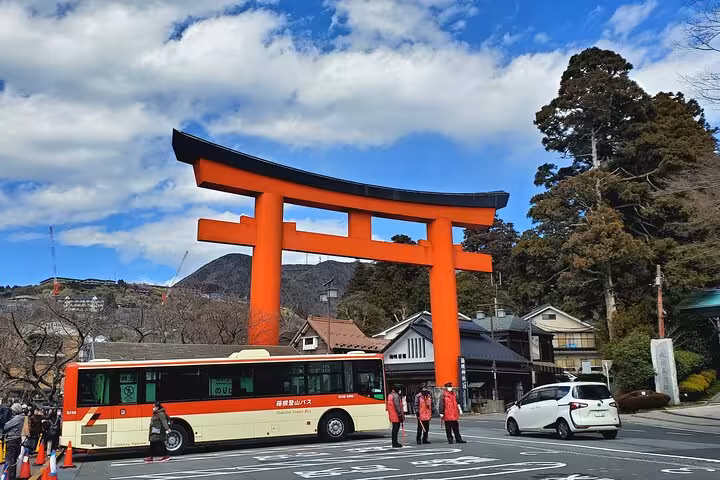 Vibrant orange torii gate with bus and visitors in Hakone, showcasing Mt. Fuji tour highlights and accessibility.
