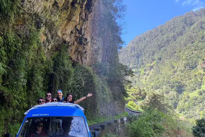 Adventurous tourists enjoy a scenic jeep tour along a lush sea cliff, part of a half-day wine tasting and exploration experience.