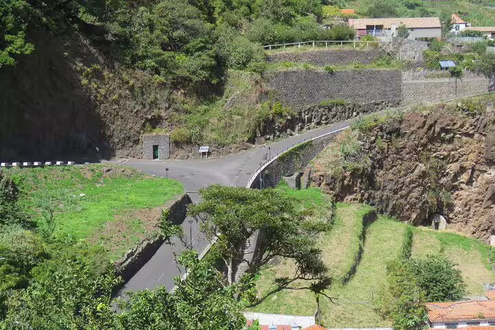 Scenic view of a winding road through lush greenery and cliffs, ideal for a half-day jeep wine tour and sea cliff adventure.