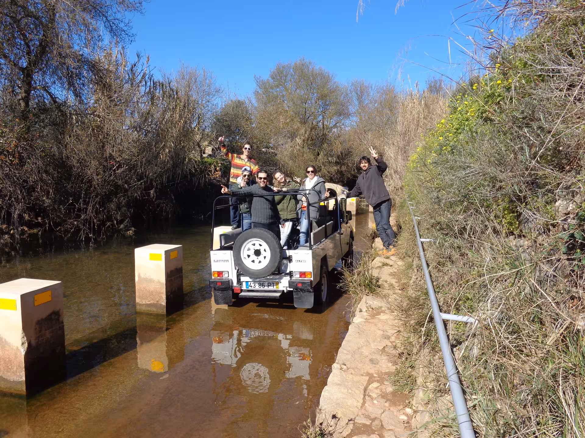 Friends in a 4x4 jeep crossing a shallow river on an off-road route included in a scenic half day wine tasting tour