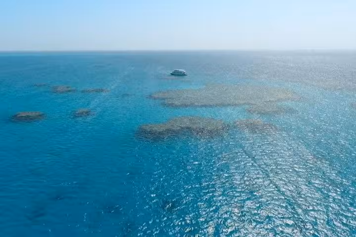 Aerial view of boat over turquoise Red Sea reefs on Hamata Island snorkeling sea trip from Marsa Alam
