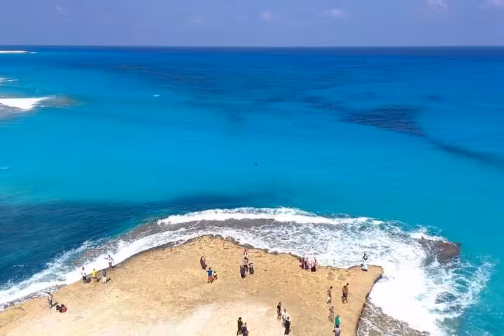 Rocky Hamata Island shoreline with snorkelers and crystal-clear Red Sea water on Marsa Alam day trip