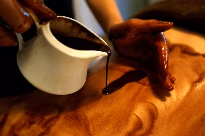 Warm oil poured during full-body massage in Sharm El Sheikh hammam spa, 120-minute relaxation treatment