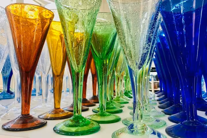 Vibrant collection of hand-blown glassware in various colors at a local glassblowing workshop on a private tour.