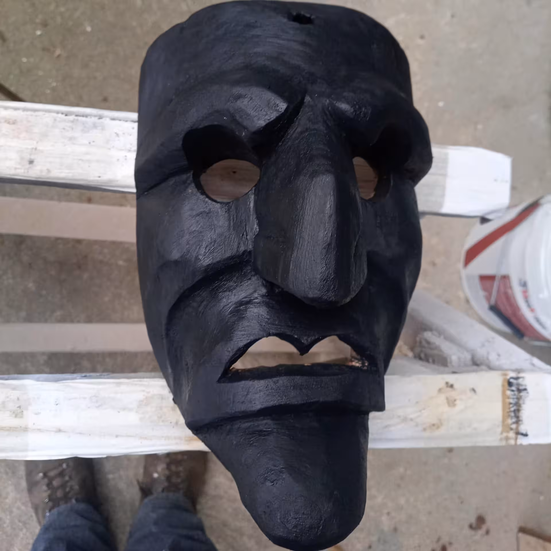 Close-up of a handcrafted black Sardinian mask, highlighting its intricate design at Mamoiada's mask workshop.