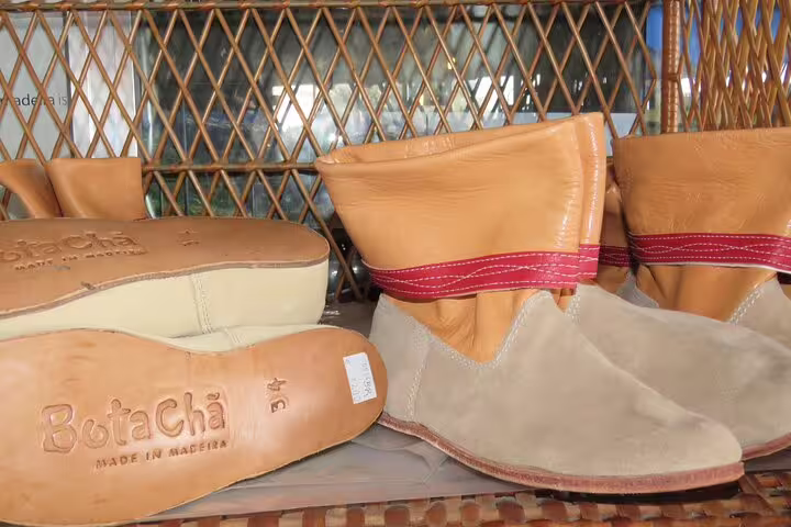 Handcrafted leather boots on display at a Funchal farmers market, showcasing local artisan craftsmanship and Madeiran culture.