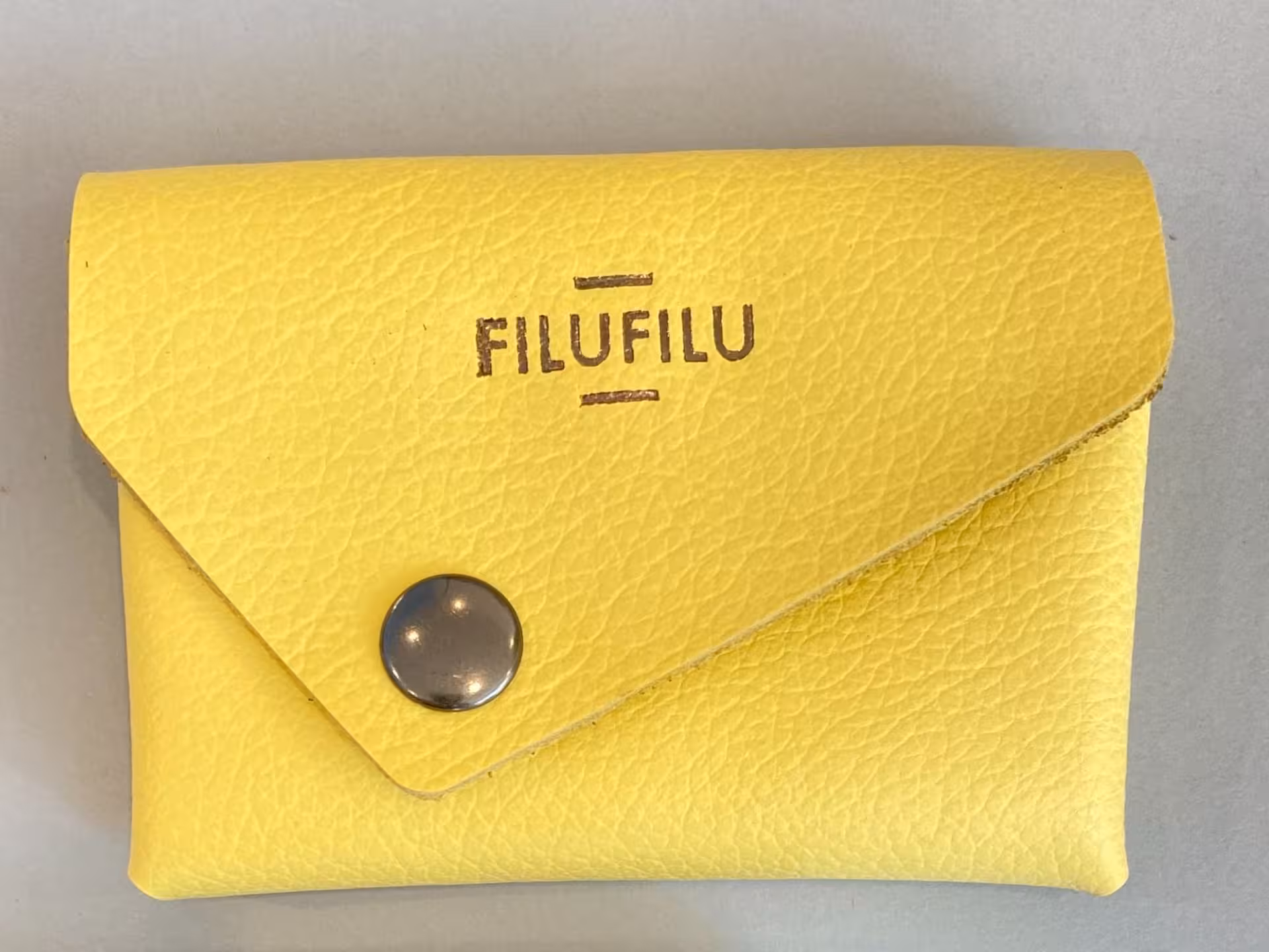 Handcrafted yellow leather wallet from Verona workshop featuring a stylish button closure for secure storage.