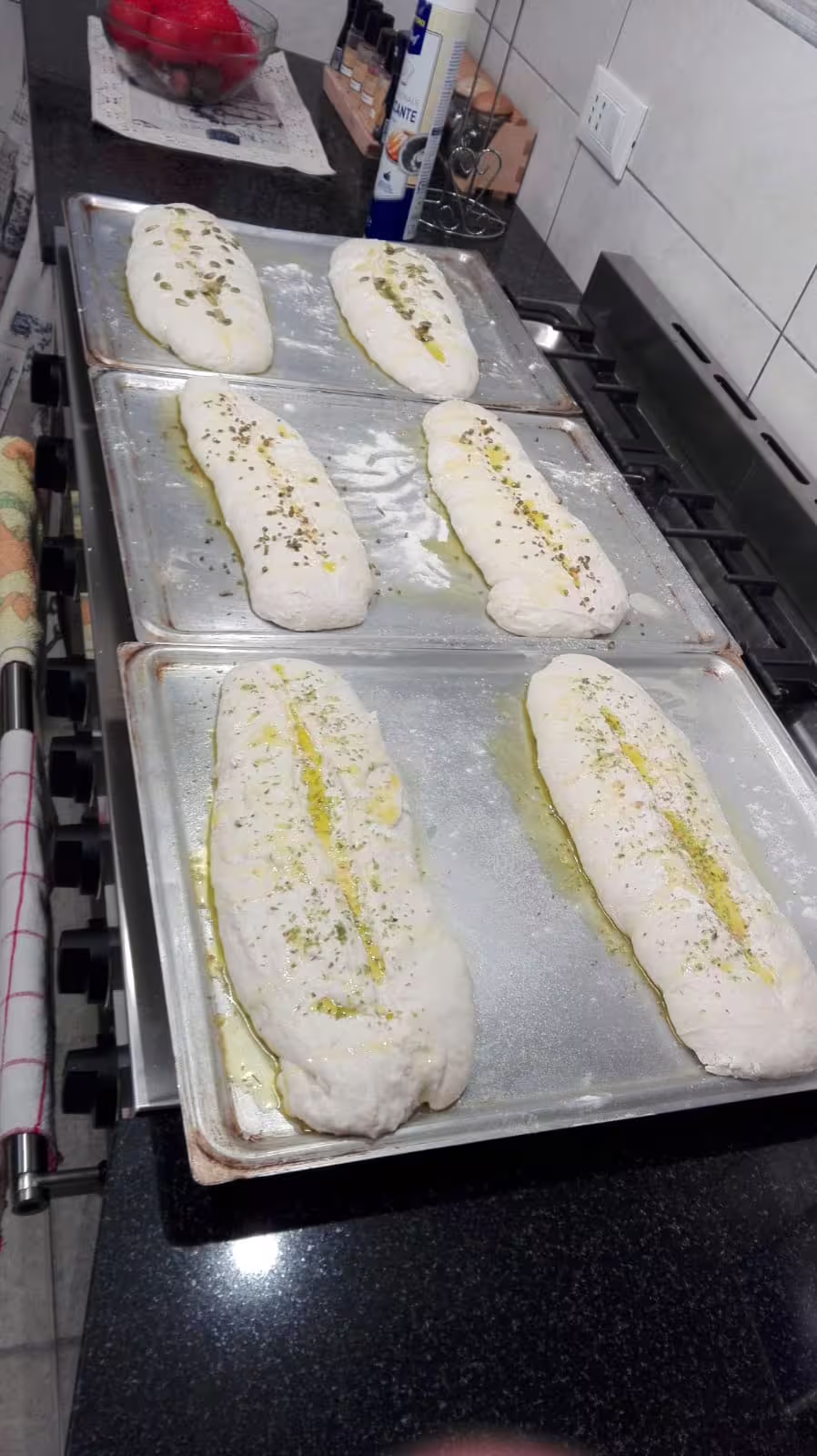 Handmade focaccia dough on baking trays, drizzled with olive oil and herbs at chef Angelo Lanaro’s home restaurant