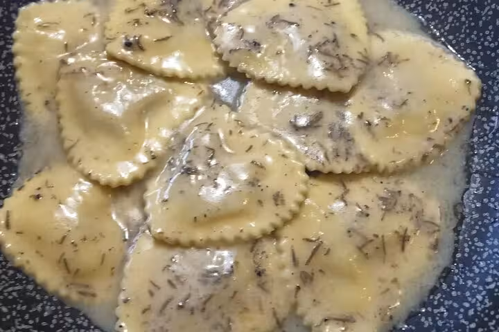 Handmade ravioli cooking in a pan with herbs during a Roman cooking class experience.
