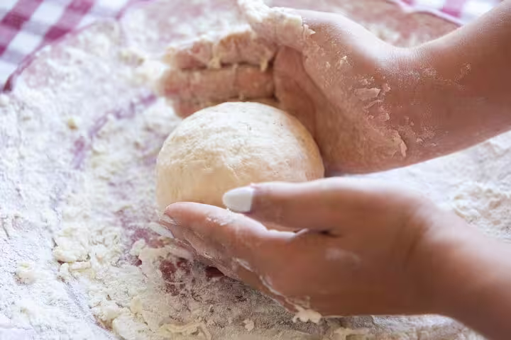 Hands kneading fresh pizza dough during farm pizza school with wine and limoncello tasting experience