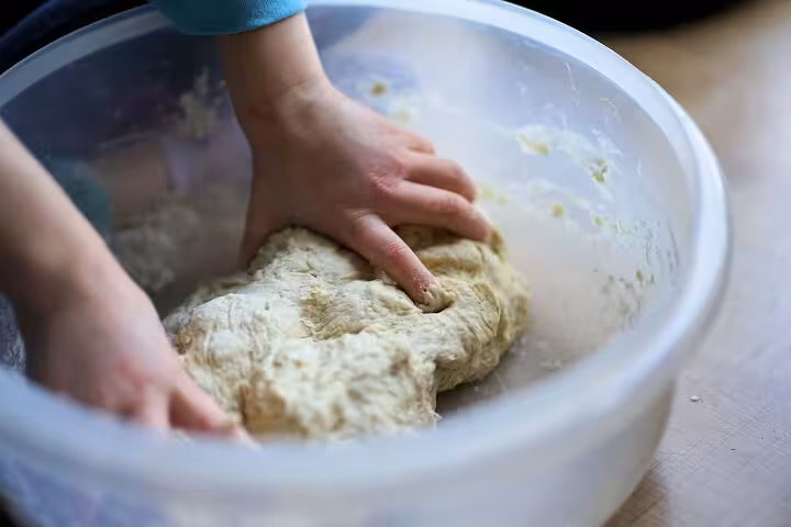 Hands kneading pizza dough in a bowl, highlighting the artisanal preparation of pizza in a Naples cooking class.