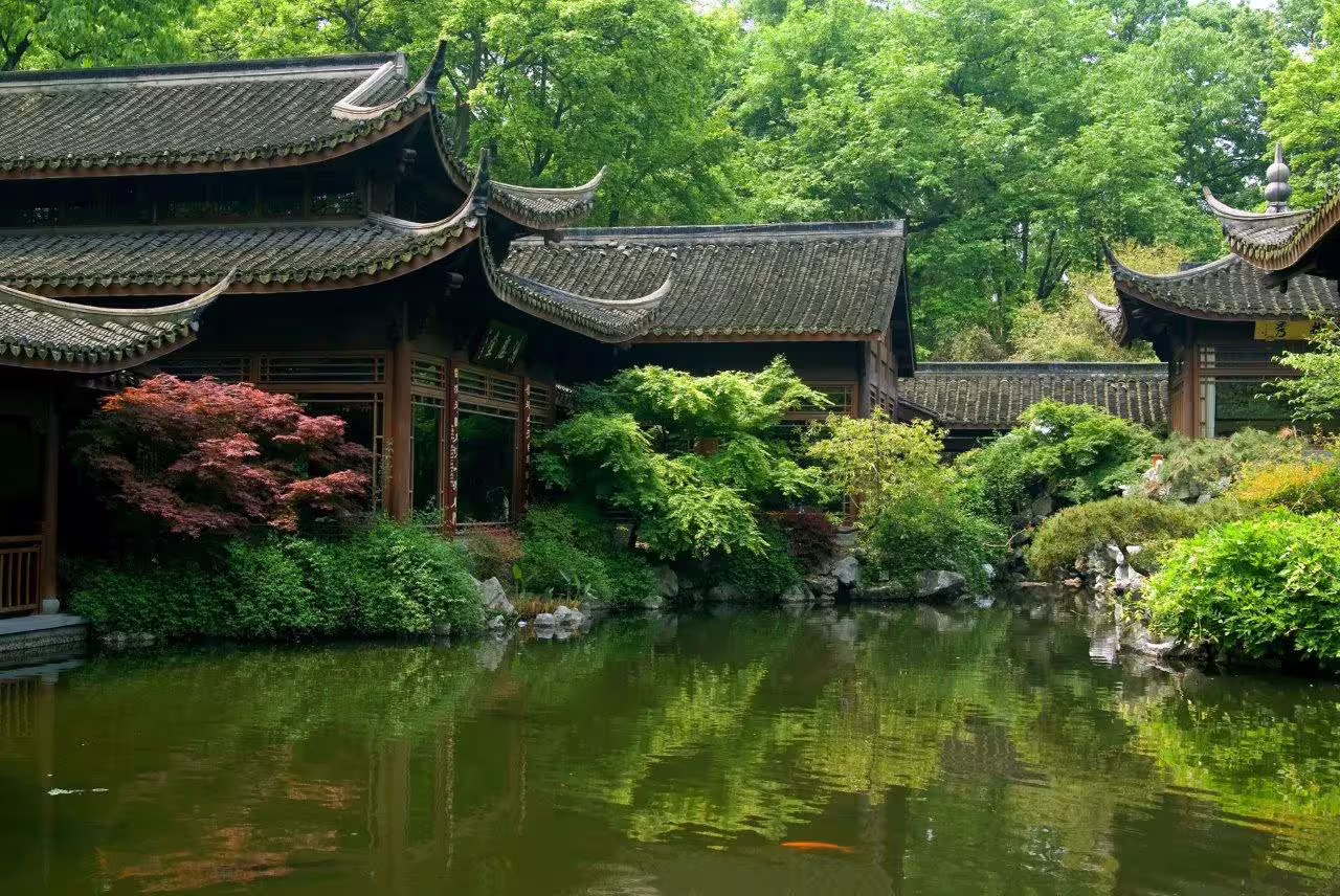 Traditional Chinese pavilion surrounded by lush greenery reflecting in serene waters at Hangzhou private tour.